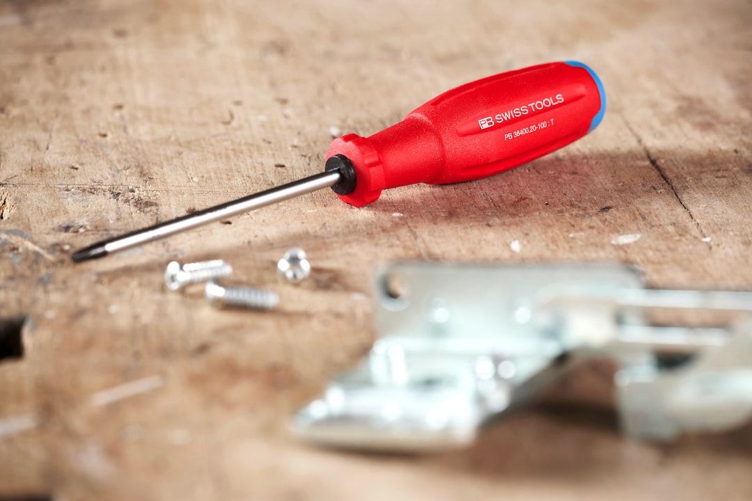 repairing toy with screwdriver - Red handled screwdriver with screws on wooden surface